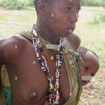Africa Tanzania Lake Eyasi Portrait of a young Hadza mother with her baby strapped to her back A small tribe of hunter gatherers Stock Photo